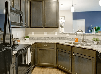 Kitchen with granite counter tops, wood-like flooring, dark color cabinets, black appliances